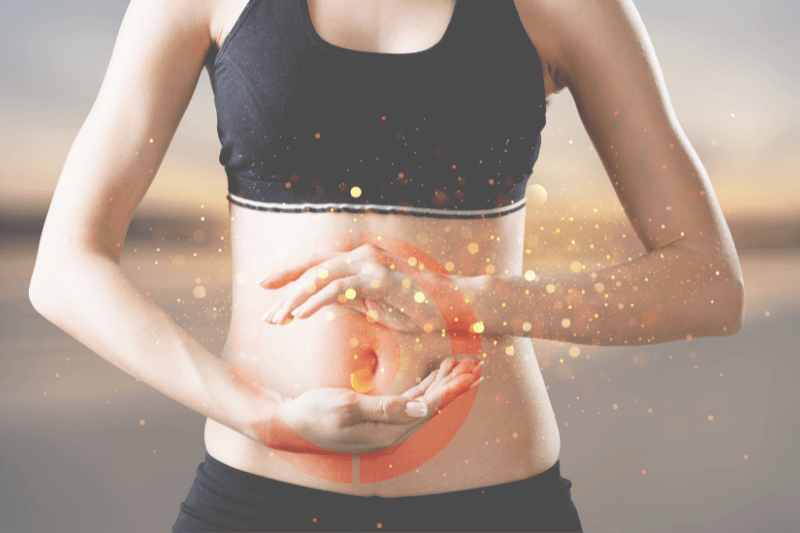 Donna in abbigliamento sportivo che poggia le mani sul ventre, con effetti grafici luminosi e simbolo di bersaglio sull’addome, a rappresentare l’importanza dell’equilibrio intestinale e della salute digestiva.