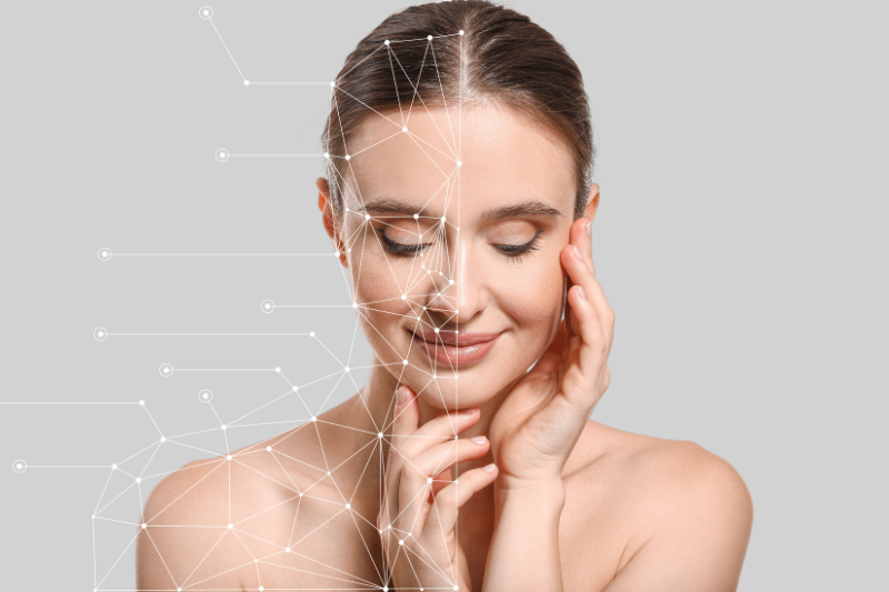 Primo piano di una donna che tocca delicatamente il viso; metà del volto è sovrapposta a una rete grafica di punti e linee che richiama struttura e analisi della pelle.