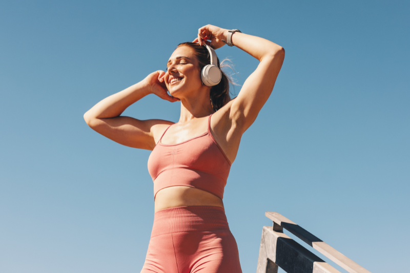 Donna in abbigliamento sportivo con cuffie all’aperto, immagine dedicata allo sport all'aperto con il caldo