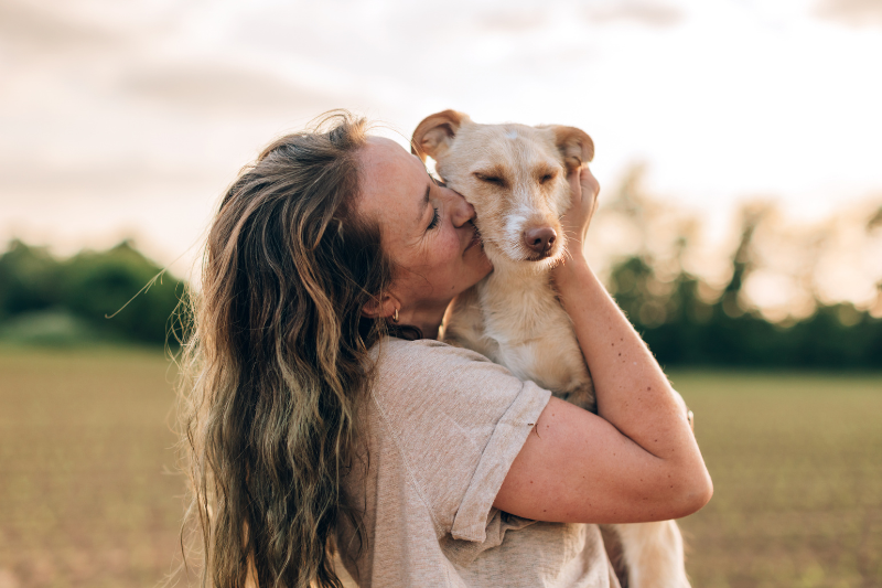 Ragazza che abbraccia e bacia il proprio cane, immagine dedicata alla Giornata Mondiale del Cane e alla cura del suo benessere.